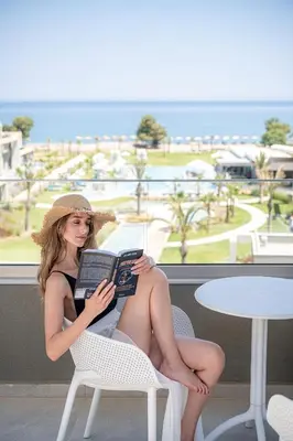 a woman sitting in a chair reading a book at Myrion Beach Resort & Spa - Adults Only in Gerani Chanion