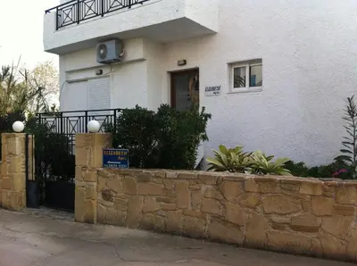 a white house with a stone wall in front of it at Paleochora Elizabeth Apartments in Palaiochóra