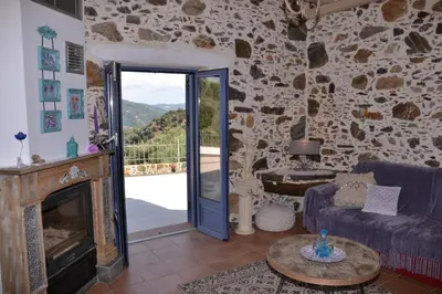 a living room with a fireplace and a stone wall at Polios in Avdhoulianá