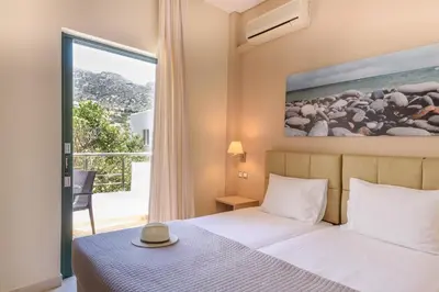 a bedroom with a bed and a large window at Hotel Poseidon in Palaiochóra