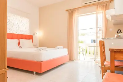 a bedroom with a bed and a large window at Nikos Rooms in Palaiochóra