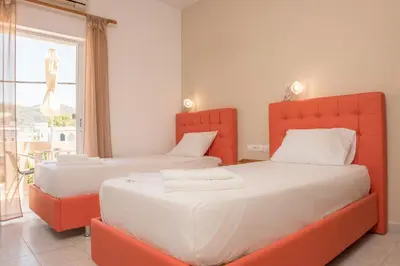two beds in a bedroom with orange and white at Nikos Rooms in Palaiochóra