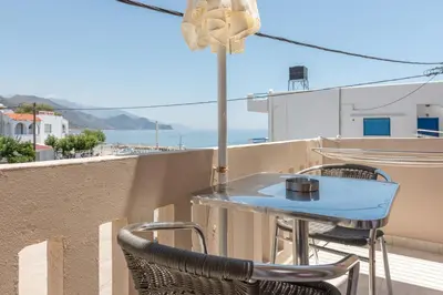 a table and chairs on a balcony with a view of the ocean at Nikos Rooms in Palaiochóra