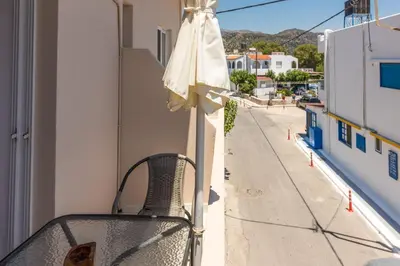 a chair sitting on a balcony with an umbrella at Nikos Rooms in Palaiochóra