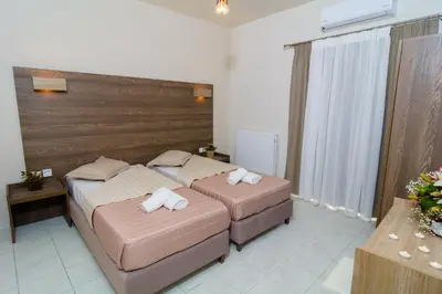 two beds in a hotel room with towels on them at Kosmos A.G.K Studios-Apts in Kato Daratso