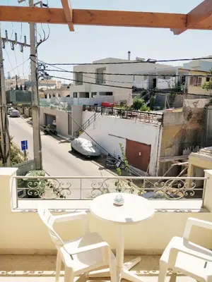 a table and chairs on a balcony with a view of a city at Alexandra Hotel in Kalamaki Chanion