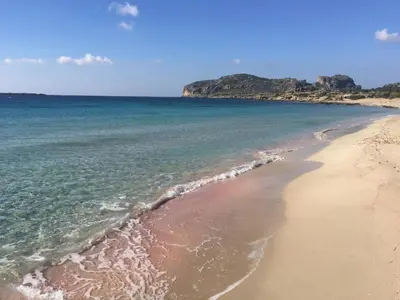 a sandy beach with the ocean and mountains in the background at Falassarna Beach studios&apartments in Falasarna