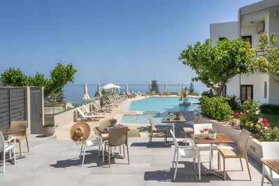an outdoor patio with tables and chairs next to a pool at Hermes Sea View in Stalos