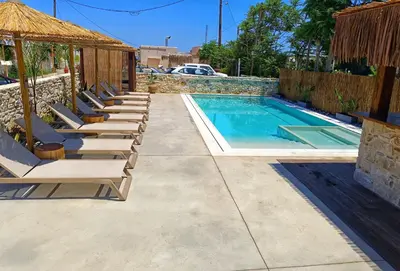 a row of lounge chairs next to a swimming pool at Miramare Boutique Apartments in Plataniás