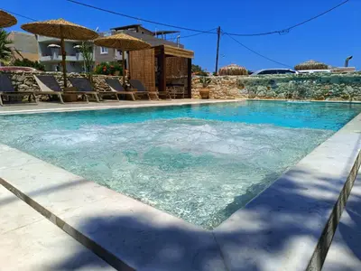 a swimming pool with blue water and chairs and umbrellas at Miramare Boutique Apartments in Plataniás
