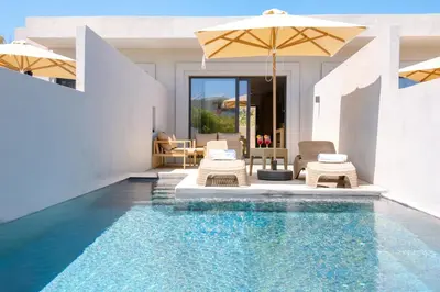 a swimming pool with chairs and an umbrella at Galini Palace in Kolymvari
