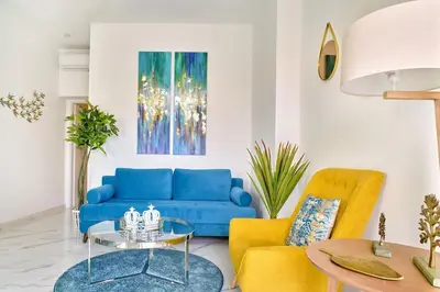 a living room with a blue couch and yellow chairs at Modern Luxury Studio Near Beach & Old Harbor Fast WiFi Private Veranda in Chania Town