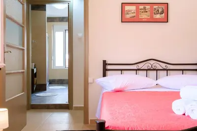 a bedroom with a bed with pink sheets and white pillows at Home with Courtyard in Beating Heart of old Town! in Chania Town