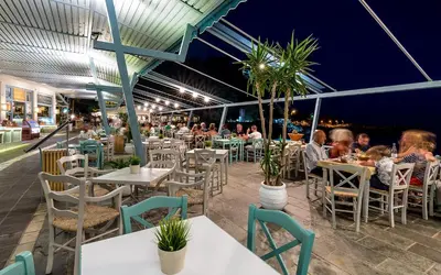 a group of people sitting at tables in a restaurant at Samaria by the Sea in Khóra Sfakíon