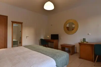 a bedroom with a bed and a desk and a mirror at Okeanis II in Kato Daratso