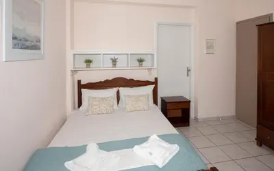a bedroom with a bed with white sheets and pillows at Maria's Hotel in Palaiochóra