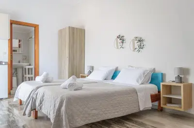 a white bedroom with two beds with towels on them at Ostria Rooms in Palaiochóra