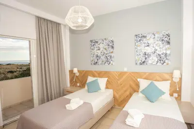a hotel room with two beds and a window at Notos Villas in Frangokastello
