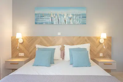 a bedroom with a white bed with two blue pillows at Notos Villas in Frangokastello