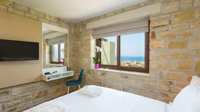 a bedroom with a stone wall with a bed and a television at Villa Emilia I Luxury, amazing seaview, next to the town in Kissamos