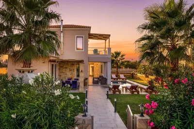 a villa with a sunset in the background at Villa Alexandros in Nopíyia