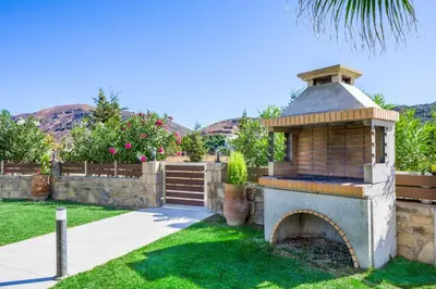 a brick oven in a yard with a fence at Villa Alexandros in Nopíyia