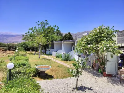 a garden with trees and a bird bath in front of a house at Ledakis Studios in Frangokastello
