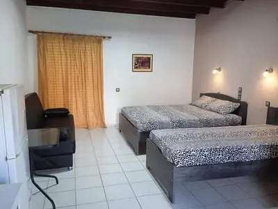 a bedroom with two beds and a couch and a window at Ledakis Studios in Frangokastello