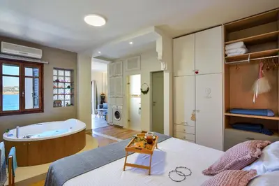 a bedroom with a tub and a bed with a table at Thalassa mou Seafront suite in Chania Town