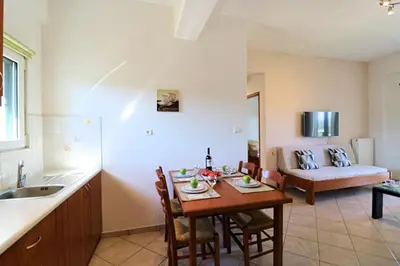 a kitchen and living room with a table and a couch at Kalimera Apartments in Vamos