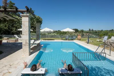 two people laying in chairs in a swimming pool at BOUTIQUE VILLA PETRA AMANDA Heated pool optional in Fílippos