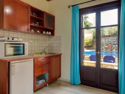 a kitchen with a microwave and a door with a window at Group Accomodation, Heliopetra Studios And Houses in Douliana