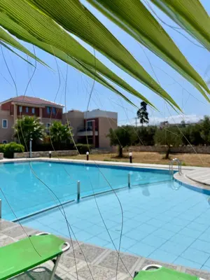 a large blue swimming pool with a green chair at Golden Victory in Agia Marina Nea Kydonias