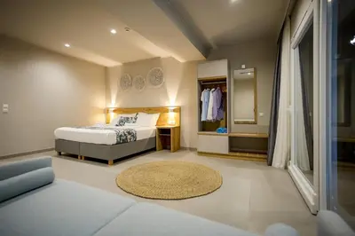a bedroom with a bed and a living room at Sarpidon Suites in Agia Marina Nea Kydonias