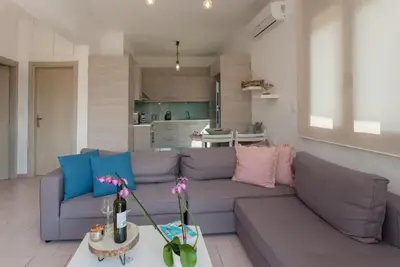 a living room with a purple couch and a kitchen at Ocean Breeze Apartments in Gerani Chanion