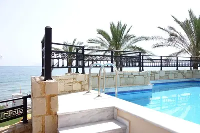 a swimming pool with the ocean in the background at Alexandra Beach Hotel in Agia Marina Nea Kydonias