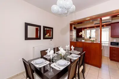 a dining room with a table and chairs and a kitchen at Voula's Place in Chania Town