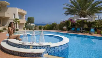 a woman is sitting next to a swimming pool at Villa Elina Luxury Residence in Stalos