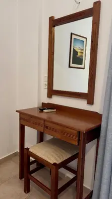 a wooden dressing table with a mirror and a stool at Mesohori studios in Sfakiá