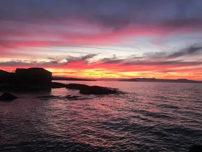 a sunset over a body of water with rocks in the water at Aristokosmos in Chania Town