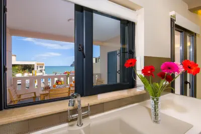 a bathroom sink with red flowers in a vase at Manolia Dream Apartment 3-bedrooms 30m to the beach in Agia Marina Nea Kydonias