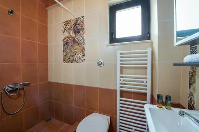 a bathroom with a toilet and a tub and a window at Manolia Dream Apartment 3-bedrooms 30m to the beach in Agia Marina Nea Kydonias