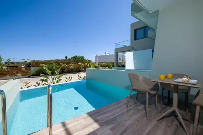 a balcony with a table and chairs and a swimming pool at Incognito Creta Luxury Suites and More in Kolymvari