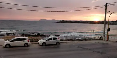 two white cars parked on a street next to the ocean at Lily of Crete 2 - Sea & Beach front Apartment in Kato Galatas