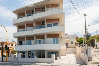 a tall white building on the corner of a street at Lily of Crete 2 - Sea & Beach front Apartment in Kato Galatas