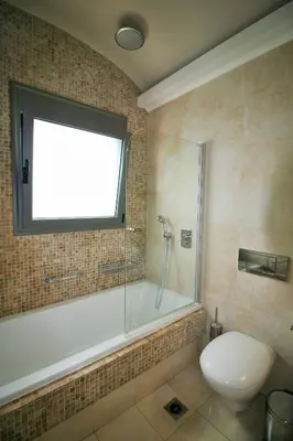 a bathroom with a tub and a toilet and a window at Amoutsa Seaside Villa in Kolymvari