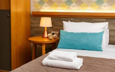 a bed with a blue pillow and a table with a lamp at Rigas City Apartment (BLUE) in Chania Town