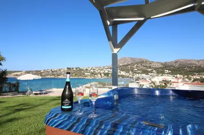 a bottle of wine sitting on a table next to a swimming pool at Villa Sea Dream Almyrida in Almirida
