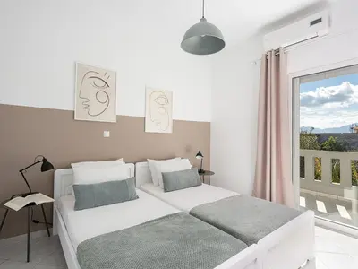 a white bedroom with a bed and a large window at Villa Kelaidis in Megála Khoráfia