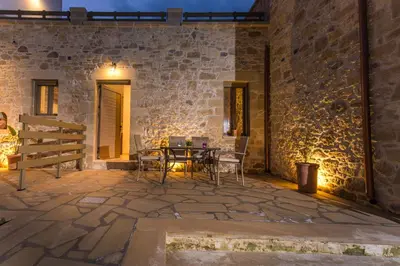 a patio with a table and chairs in a stone wall at Agarathos Deluxe Homes In the Heart of Kaliviani Near Balos in Kissamos